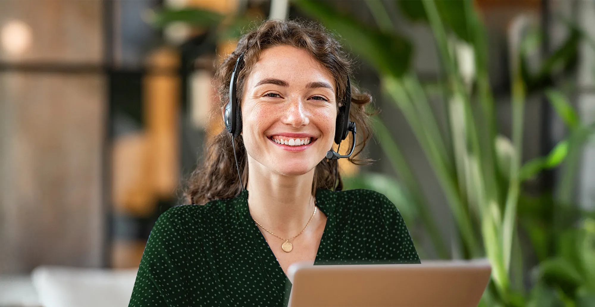 Lächelnde Frau mit Headset am Laptop